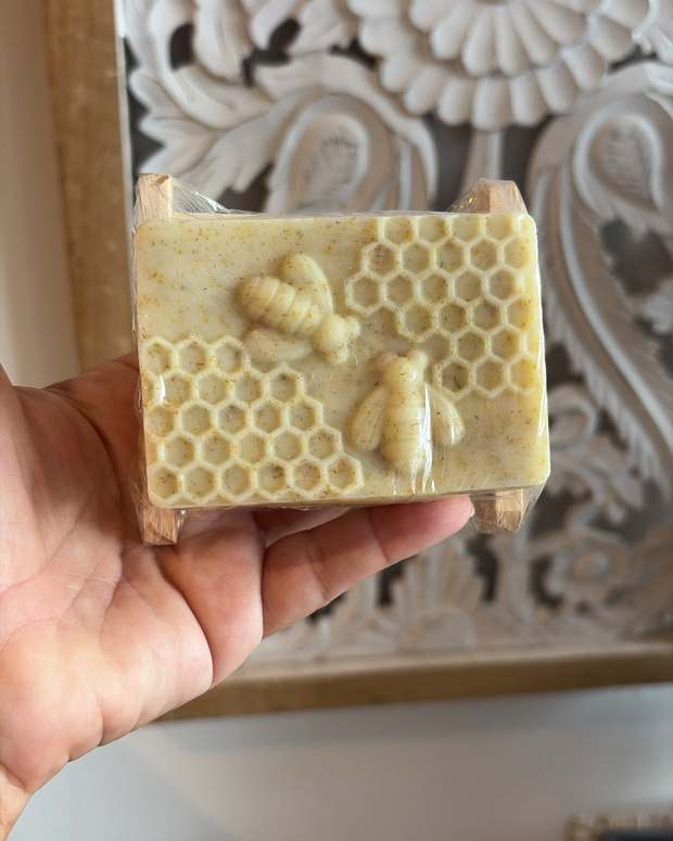 Handmade honeycomb glycerin soap with small bees on top, held in a hand